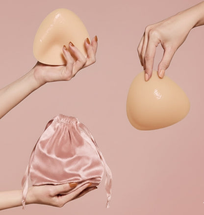 Ultra Boostelle Silikon-Brusteinsätze für Push-up-Effekt, in der Hand gehalten, inklusive rosafarbenem Satin-Aufbewahrungsbeutel. Perfekt für BH und Bikini, unsichtbarer Boost.